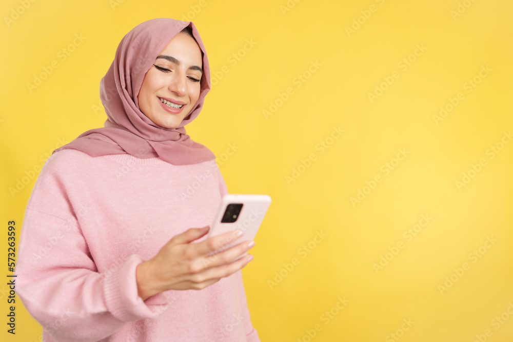 Happy muslim woman smiling while using a mobile phone Happy muslim woman smiling while using a mobile phone