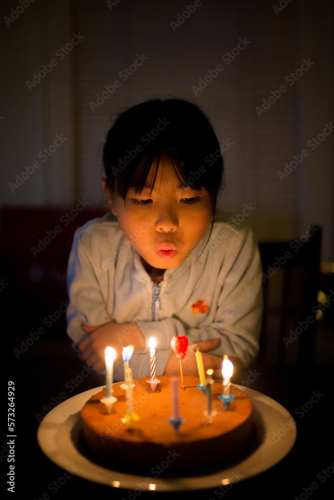 Young asian girl blowing candles on homemade birthday cake Young asian girl blowing candles on homemade birthday cake