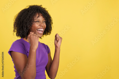 Happy woman with afro hair celebrating while raising fists