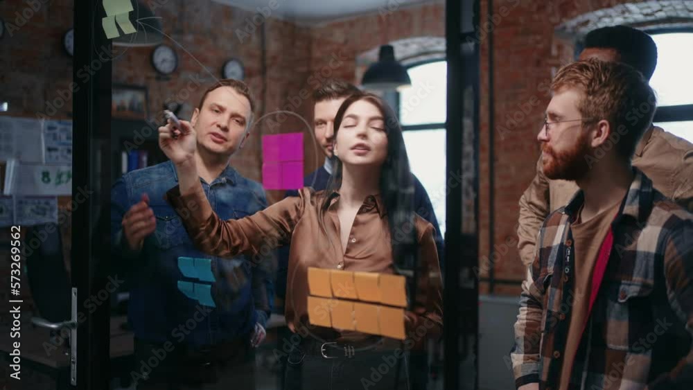 SEO Specialist Woman Sharing Idea With Co-Workers In Office, Drawing, Showing Post-It On Glass Wall SEO Specialist Woman Sharing Idea With Co-Workers In Office, Drawing, Showing Post-It On Glass Wall