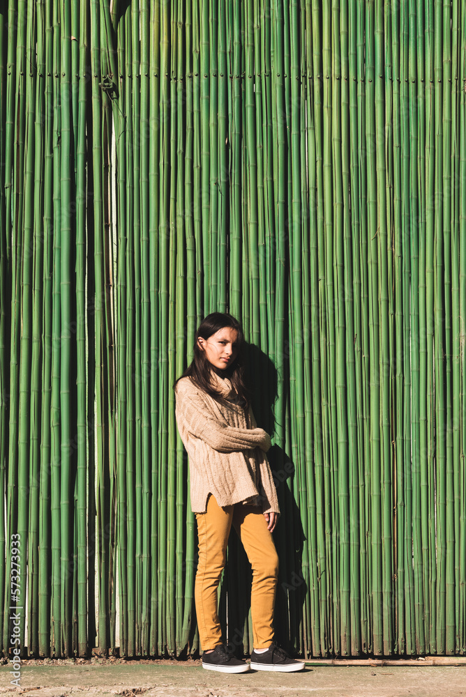 mujer adolescente posando sola en pared verde de cañas
