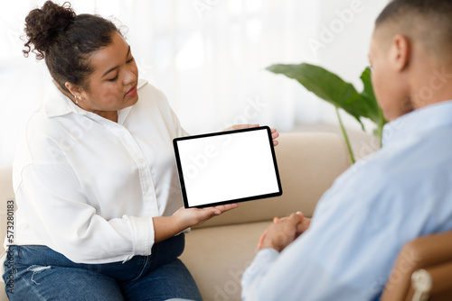 Mixed race woman therapist showing male patient digital tablet, mockup