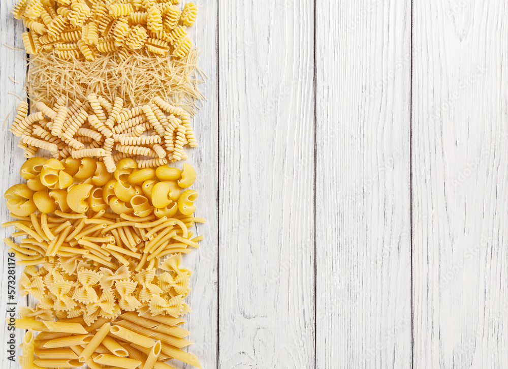 Different types and shapes of Italian pasta on white wooden background