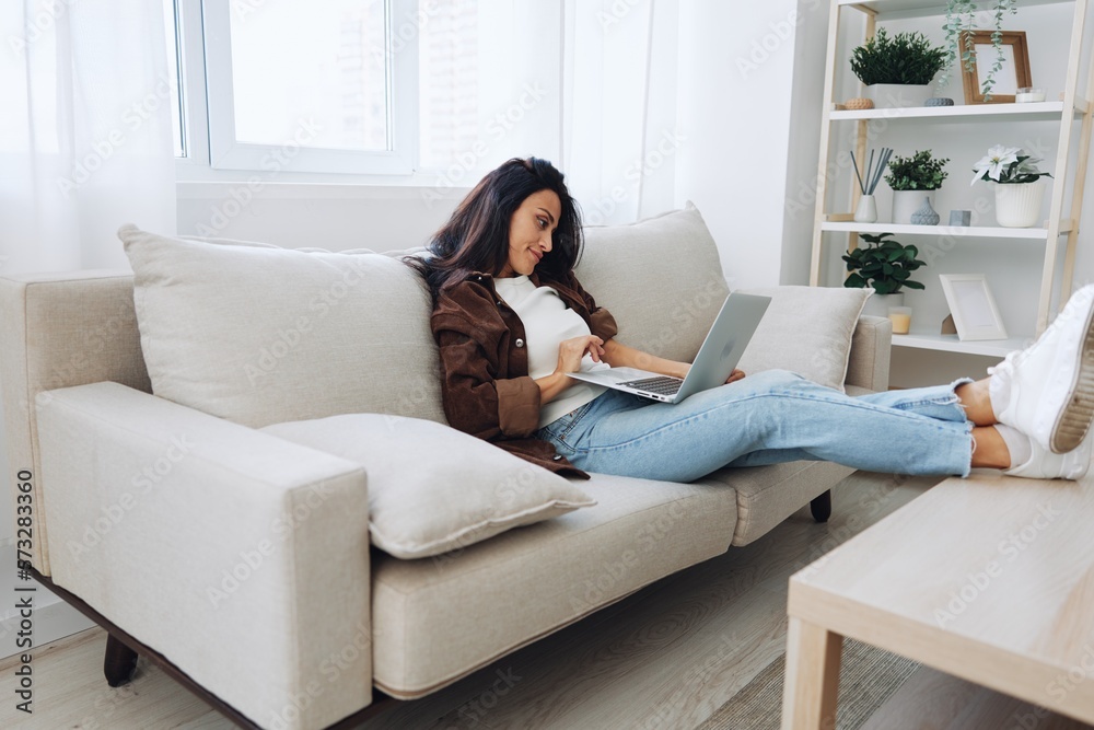 Woman freelancer on day off sitting on sofa with laptop at home online shopping on internet, smile Woman freelancer on day off sitting on sofa with laptop at home online shopping on internet, smile