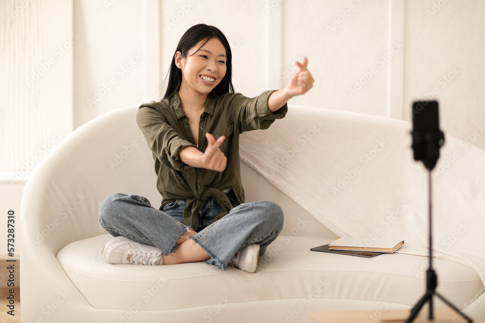 Cute chinese female vlogger gesturing, recording content for followers Cute chinese female vlogger gesturing, recording content for followers