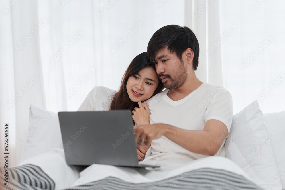 Beautiful asian couple in love and smiling sitting on bed. Romantic moment, relationships, family concept.
