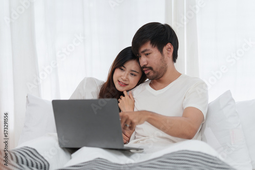 Beautiful asian couple in love and smiling sitting on bed. Romantic moment, relationships, family concept.