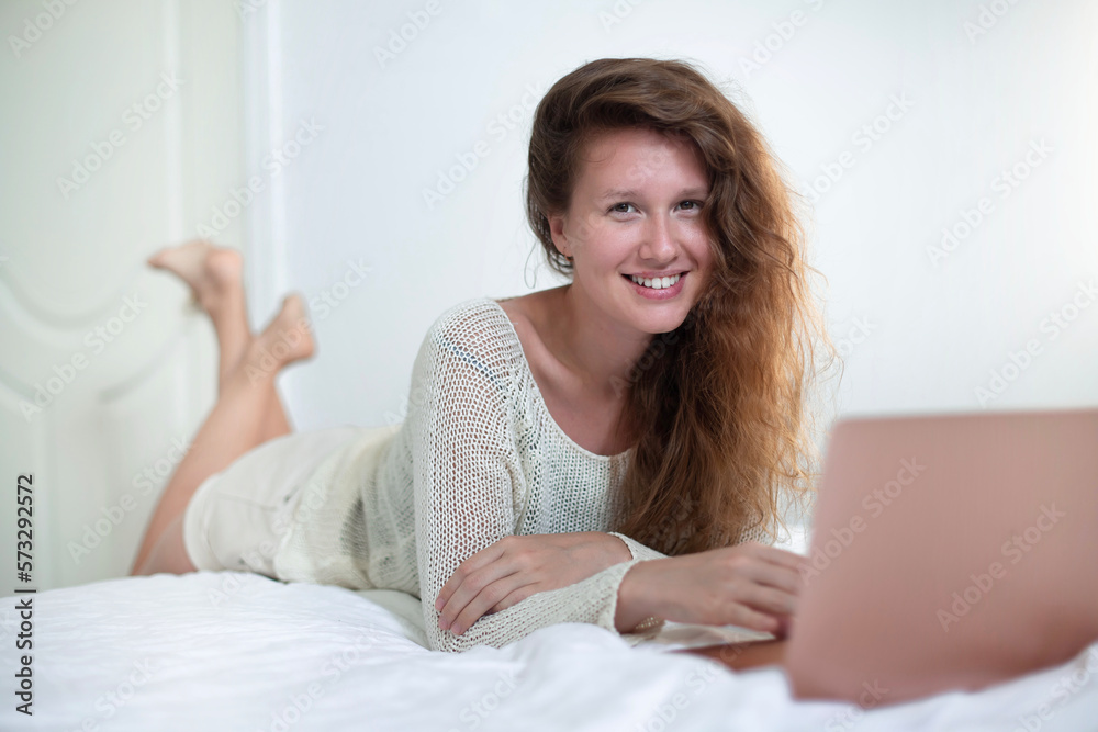 Happy joyful woman is using laptop computer at home on bed in bedroom and smiling Happy joyful woman is using laptop computer at home on bed in bedroom and smiling