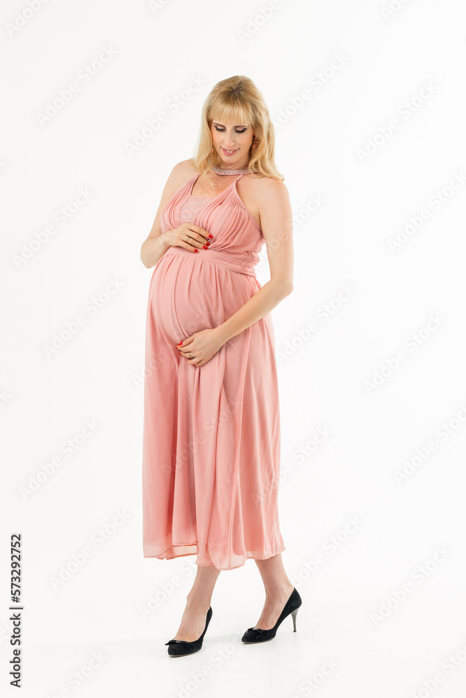 A pregnant woman holds her hands on her stomach on a white background. The concept of pregnancy, motherhood, preparation and expectation. Beautiful photo during pregnancy.