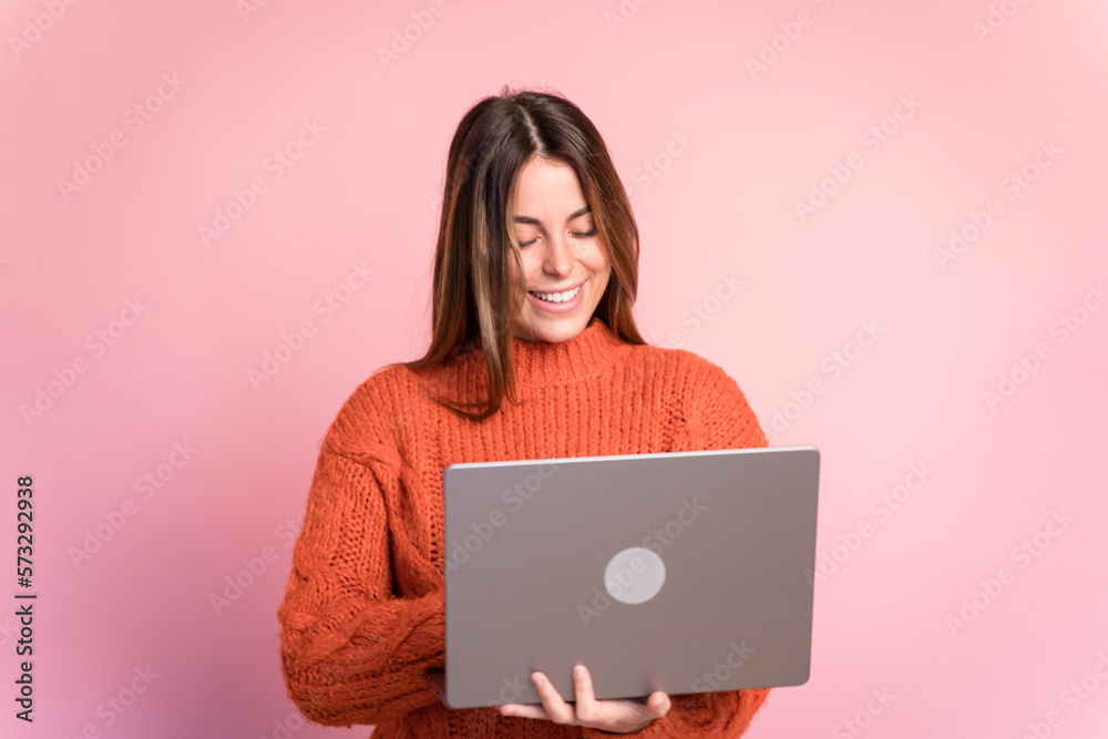 Smiling woman with laptop against pink background Smiling woman with laptop against pink background