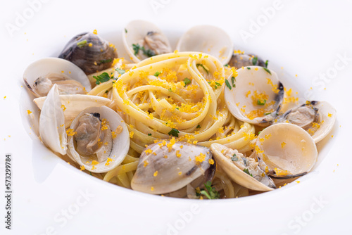 Spaghetti pasta with clams (vongole) and  bottarga (dried tuna or mullet caviar) on a white table. Classic seafood dish of the Sardinia, Sicilli islands and Napoly. Italian healthy cuisine, close up photo