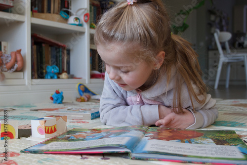 Little cute girl reading a book in the room. Education at home concept