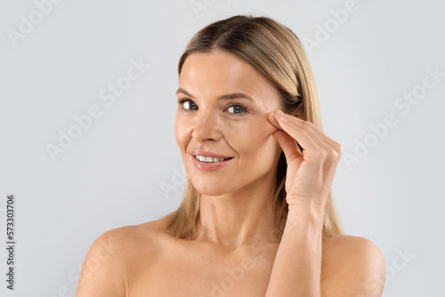 Closeup of blonde middle aged woman playing with face skin photo