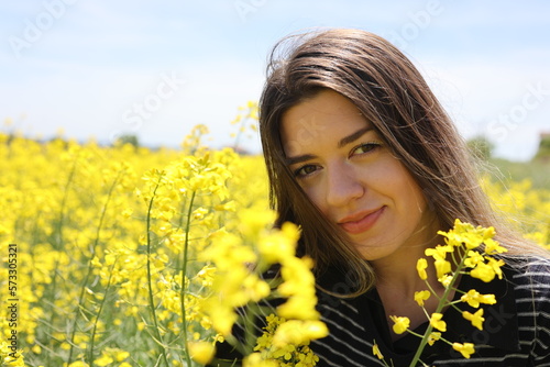 Happy beautiful young woman in yellow canola field.