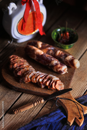 Traditional Chinese preserved sausage and pork, cut in slices in a vintage cutting board, peanuts in the center for wine drinking - dark and moody still life. photo