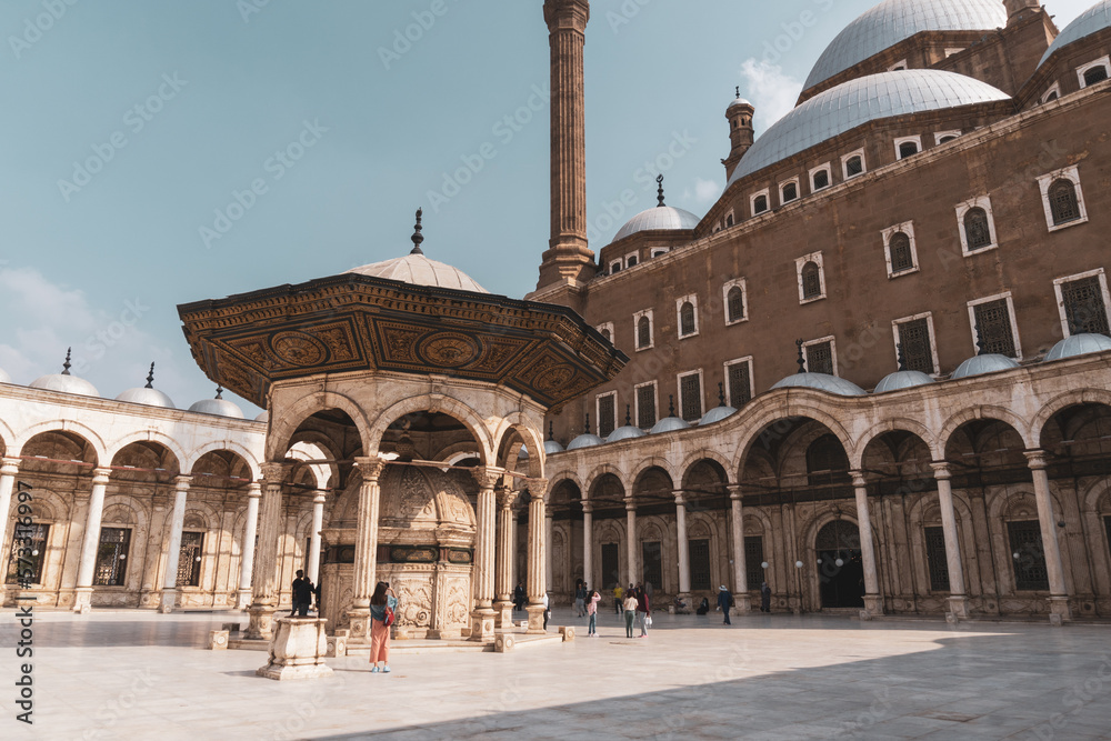 Inner courtyard of the Alabaster Mosque in Cairo on a sunny day, with some tourists.