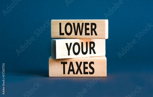 Lower your taxes symbol. Concept words Lower your taxes on wooden blocks on a beautiful grey table grey background. Business tax lower your taxes concept. Copy space. © Dzmitry