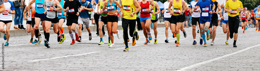 large group of runners athletes run city marathon on cobblestones