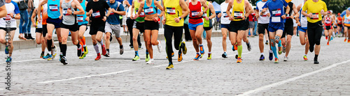 large group of runners athletes run city marathon on cobblestones