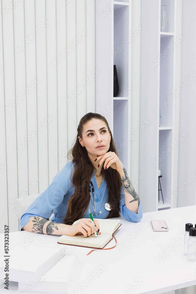 This photo shows a cosmetic dermatologist taking notes at her desk, surrounded by plants, books, and accessories. Her blue coat and professional focus convey a sense of clinical precision. This photo shows a cosmetic dermatologist taking notes at her desk, surrounded by plants, books, and accessories. Her blue coat and professional focus convey a sense of clinical precision.