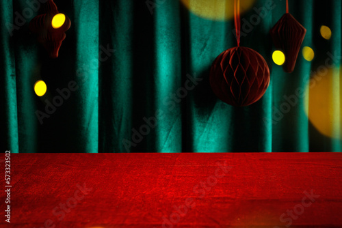 Christmas and New years eve Background with empty red cloth table and green draped velvet curtains with Red balls . Template for advertising, presentation, cosmetic products. Mockup, texture.