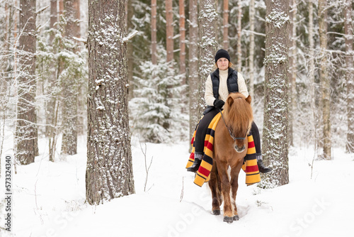 Icelandic horse and female rider in snowy Finnish forest