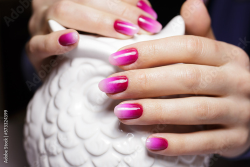 Women's hands with a gradient pink manicure. Nail design, manicure with gel polish 