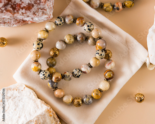 a bracelet made of lace agate and jasper, an agate stone with patterns, a soothing mineral, Jasper will help in the implementation of plans and will protect. silk beige background.