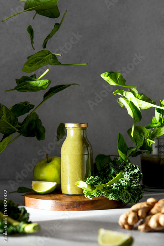 Green smoothies concept with flying leaves of spinach around the bottle with ready to drink raw and healthy ingredients blend