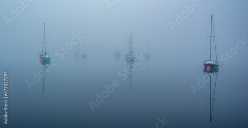 Misty view of yachts moored on a still lake at dawn