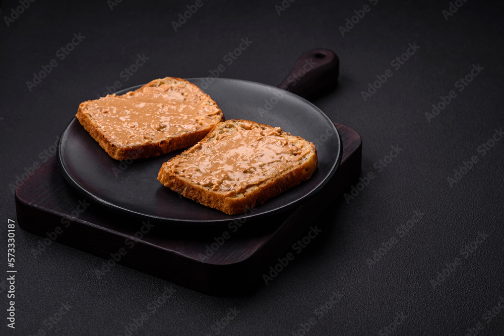 Nutritious sandwich consisting of bread and peanut butter on a black ceramic plate Nutritious sandwich consisting of bread and peanut butter on a black ceramic plate