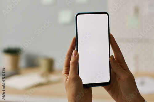 Minimal close up female hands holding smartphone with white screen mock up