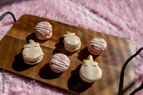 Overhead pink and unicorn macarons on wooden tray with pink background