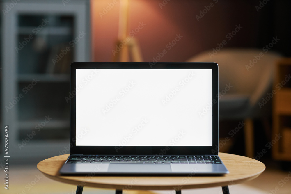 Fototapeta premium open laptop with white screen mockup in dim home interior