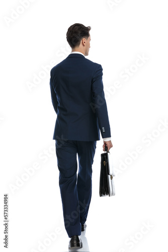 businessman walking, looking away and holding briefcase