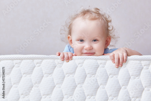 Baby on the bed mattress close-up. The sidewall of the mastras is stitched with finishing lines.