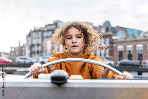 A girl at the wheel of a boat on a canal in Amsterdam