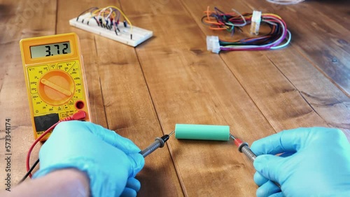 A man measures a li ion battery with a multimeter.