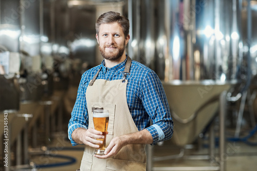 Bearded man holding beer glass at brewing factory