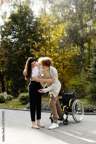 Wallpaper Mural Attractive, young girl helps a young man to get up from a wheelchair. Young couple outdoors. Torontodigital.ca