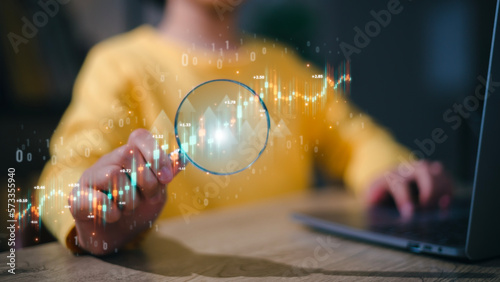 stock market for analysis of technical graphs. Woman hand holding magnifier glass with virtual stock market chart, Business investment earning income concept.