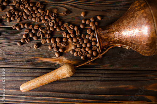 Turkish copper cezve and coffee beans on a wooden background. The concept of freshly brewed coffee. photo