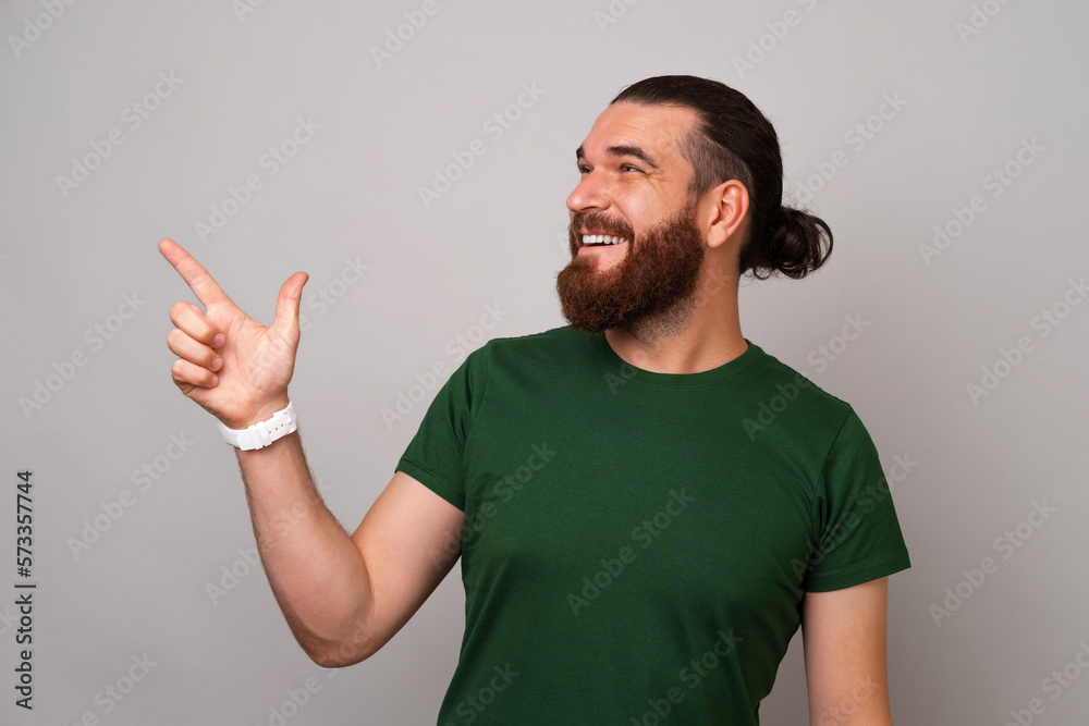Studio shot of a handsome man wearing green and pointing up at copy space over grey background. Studio shot of a handsome man wearing green and pointing up at copy space over grey background.