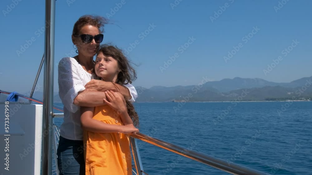 Parents boating yacht in turquoise sea. A woman hugs her little girl on the boat nose during sea trip against water view. Parents boating yacht in turquoise sea. A woman hugs her little girl on the boat nose during sea trip against water view.