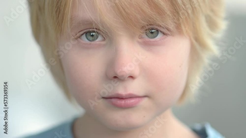 Close-up portrait of sad and thoughtful school-age child. The cute boy closed his eyes, then opened them and looks at you very seriously. Upset, offended and lonely kid photo