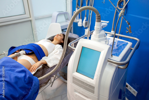 coolsculpting procedure in cosmetology clinic, girl patient lies on couch connected to the machine to remove fat photo