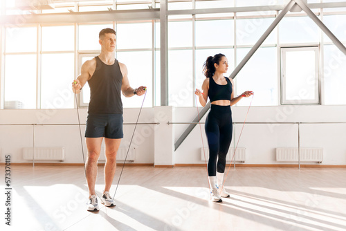 athletic couple in training jump rope in the gym in the morning  man coach and woman go in for sports