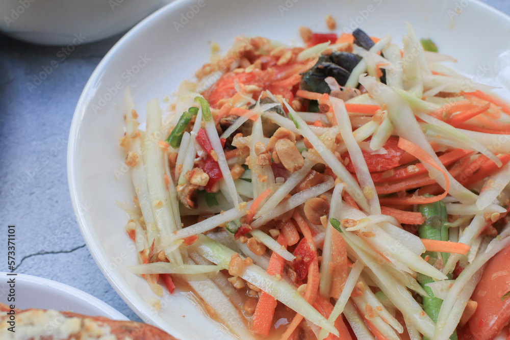 Thai papaya salad, Som Tum, Spicy green papaya salad with vegetables on table. Famous Thai food. Asian food style Thai papaya salad, Som Tum, Spicy green papaya salad with vegetables on table. Famous Thai food. Asian food style