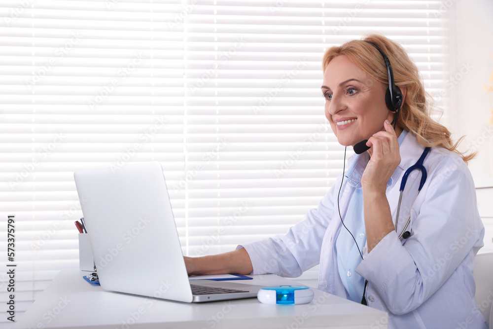 Doctor with laptop and headphones consulting patient in clinic. Online medicine concept Doctor with laptop and headphones consulting patient in clinic. Online medicine concept