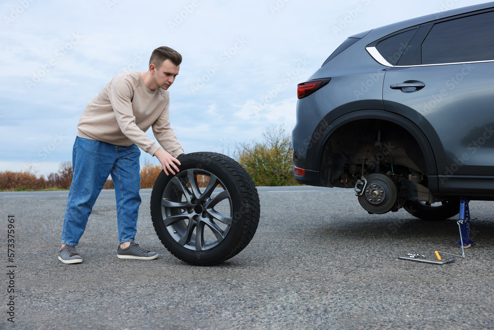Young man changing tire of car on roadside Young man changing tire of car on roadside